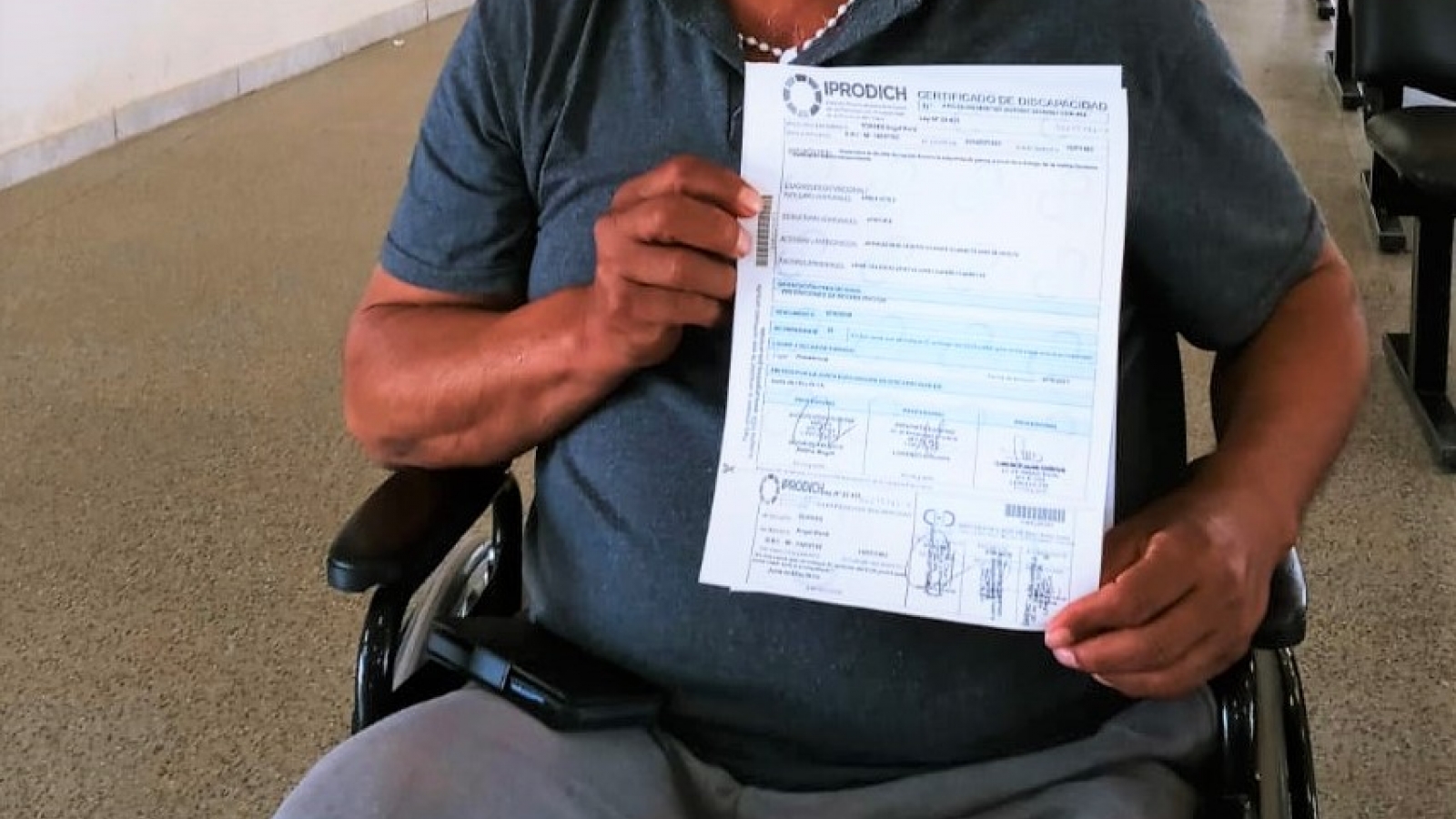 Persona en silla de ruedas mostrando su certificado de discapacidad obtenido
