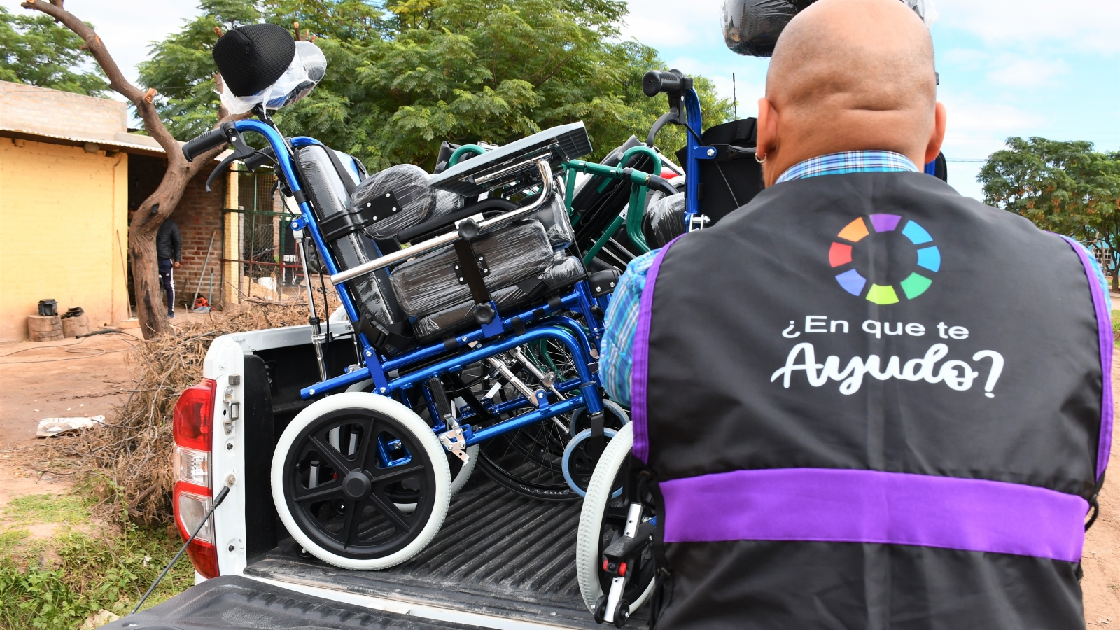 Personal de IPRODICH de espalda, bajando una silla de ruedas de camioneta