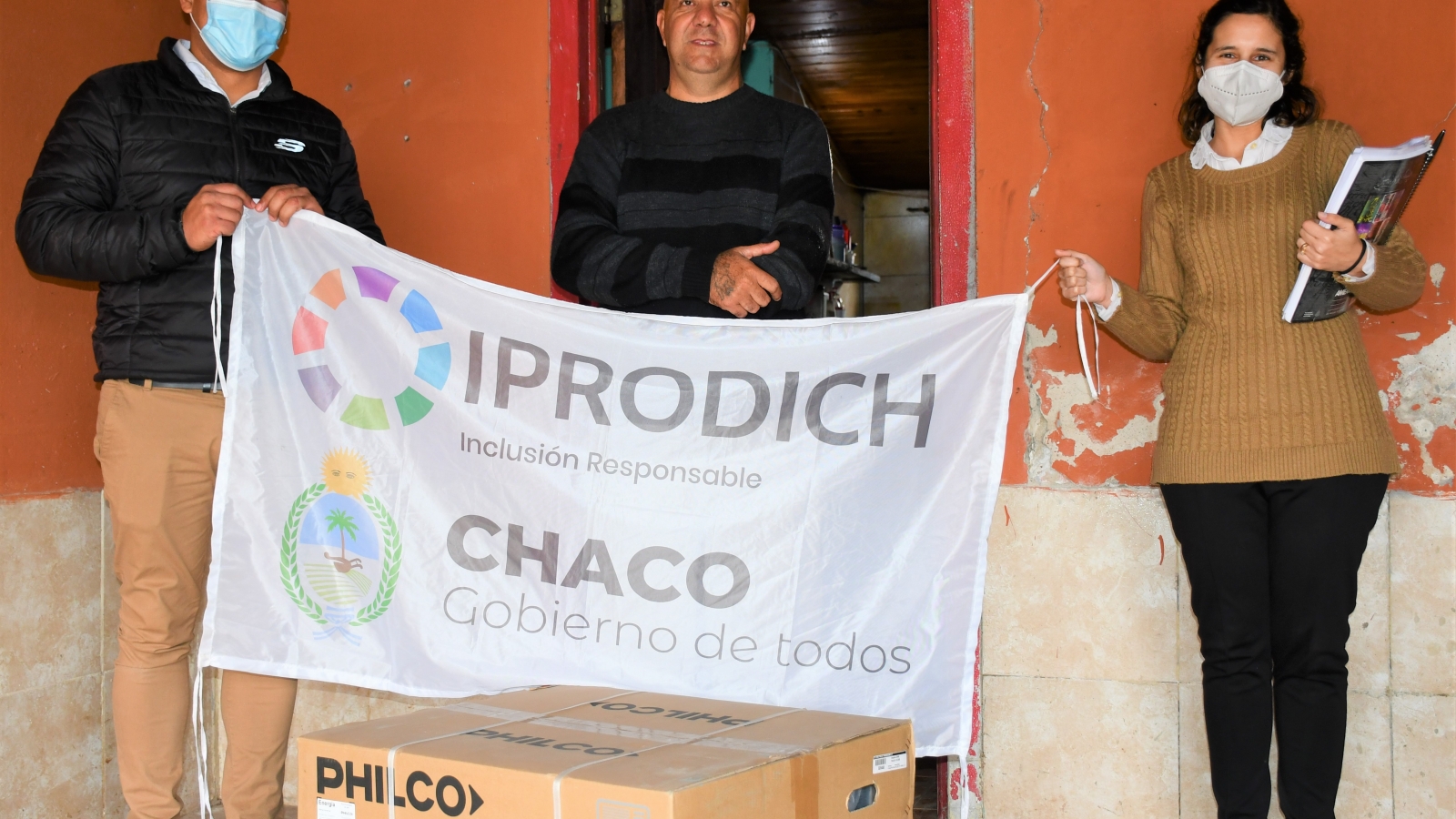 Trabajadores del IPRODICH entregando un aire acondicionado a beneficiario